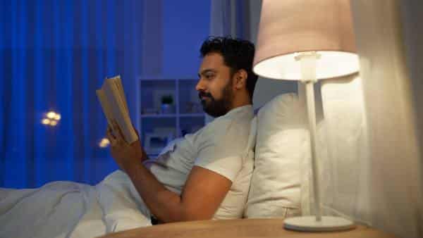man-in-bed-at-night-reading-with-lamp-turned-on