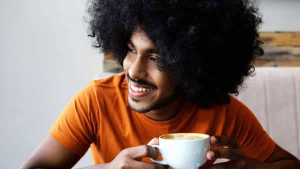 man in orange shirt and curly hair with coffee edit
