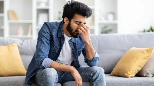 south asian man depressed sitting on couch.jpg