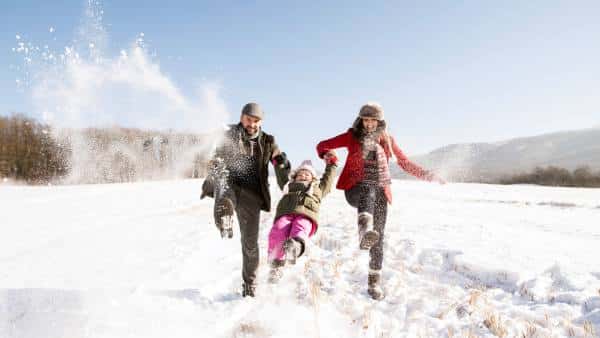 Father and mother with their daughter playing in the snow